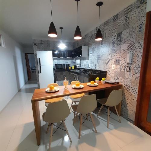 a kitchen with a wooden table and four chairs at FLAT a 2min do relogio da flores com ar condicionado in Garanhuns