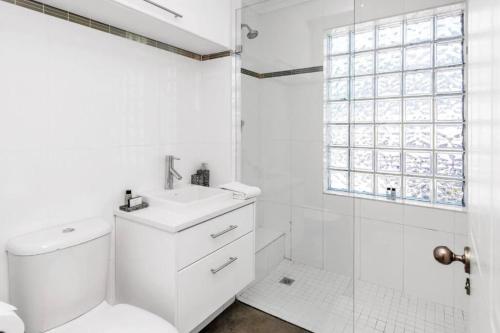 y baño blanco con aseo y ducha. en Cosy New Home in Claremont en Ciudad del Cabo