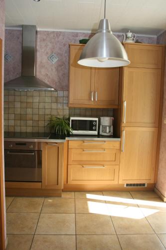 a kitchen with wooden cabinets and a silver light fixture at The BlackSmith's House in Libin