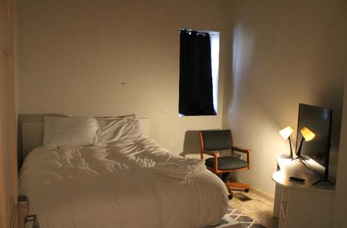 a bedroom with a bed and a chair and a window at Private room in the heart of Oakland in Pittsburgh