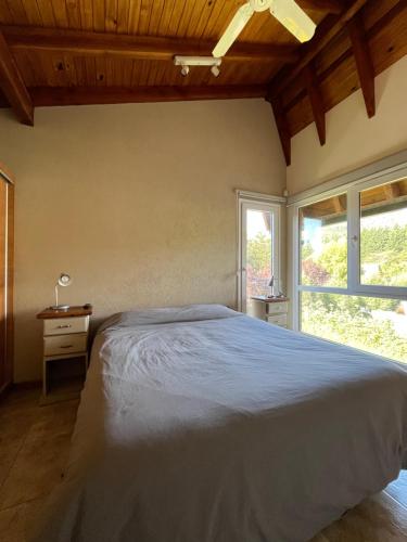 um quarto com uma cama grande e uma janela em Balcones de Montaña em Villa La Angostura
