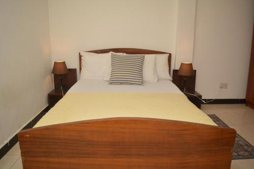 a bedroom with a bed with a wooden headboard at Amareen Apartments in Accra