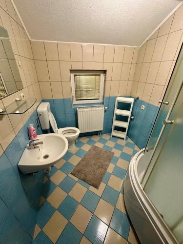 baño azul y blanco con aseo y lavamanos en Apartmani Ivan en Kupres