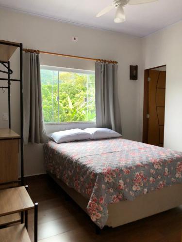 a bedroom with a bed and a large window at Pousada Refúgio das Flores in Ubatuba