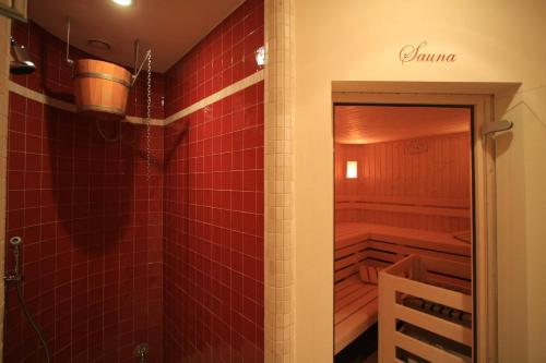 bagno con doccia e pareti con piastrelle rosse di Hotel Garnì Carpe Diem a Vigo di Fassa