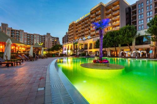uma grande piscina com iluminação verde numa cidade em 2 Bed, Royal Beach Barcelo Hotel em Sunny Beach