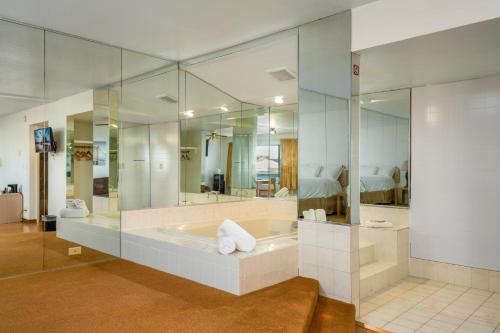 ein großes Bad mit einer Badewanne und einem großen Spiegel in der Unterkunft Alsi Resort Hotel in Waldport