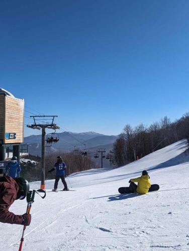 a group of people sitting in the snow on a ski slope at Chalet 86 - 3 Minutes From Whiteface Mountain in Wilmington