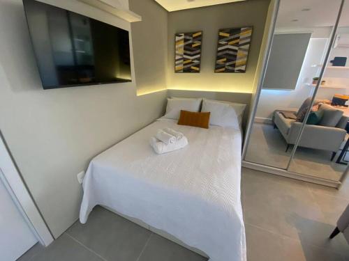 um quarto com uma cama branca e um espelho em Super compacto aconchegante. em Porto Alegre