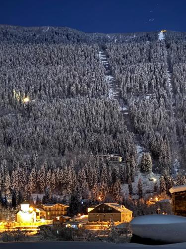 una colina cubierta de nieve con una estación de esquí por la noche en Villa Dabderr Mestia, en Mestia