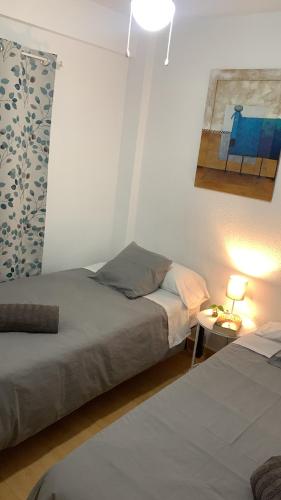 1 dormitorio con 2 camas y mesa con lámpara en Harmony room málaga, en Málaga