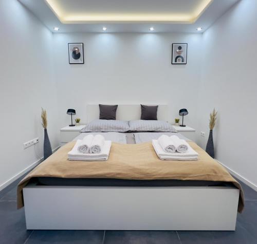 a white bedroom with a large bed with towels on it at Apartment K21 - Győr in Győr