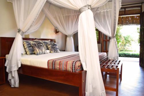 a bedroom with a canopy bed with curtains at African Roots Gulu in Gulu