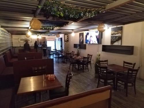 a restaurant with wooden tables and chairs and a bar at NN Jacaranda Guesthouse in Newcastle