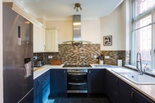 a kitchen with blue cabinets and a stove top oven at Stylish City Centre 2 Bed Apartment - Free Parking in Manchester