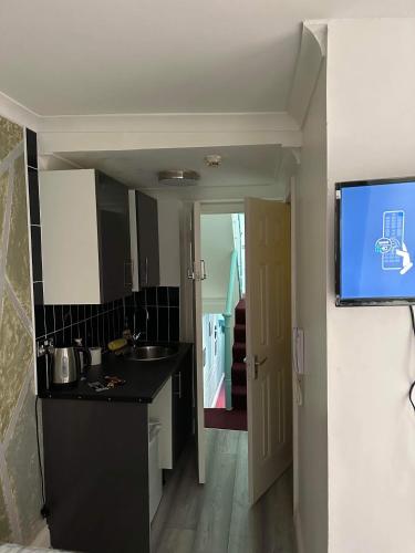uma cozinha com um lavatório e uma televisão na parede em Single Room 9 em Londres