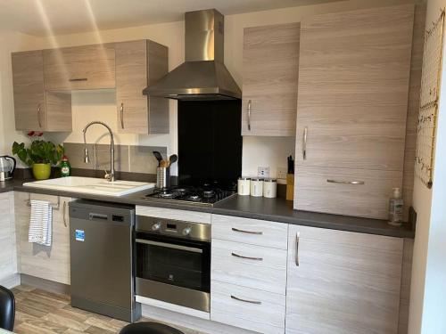 una cocina con electrodomésticos de acero inoxidable y armarios de madera en Modern 3bed house in central location & free parking en Aberdeen