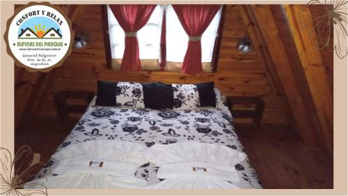 ein Schlafzimmer mit einem Bett mit schwarzen und weißen Kissen in der Unterkunft Cabana Alpinas del Parque in General Belgrano