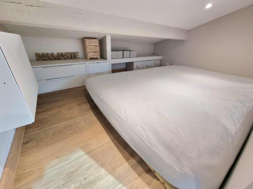 1 dormitorio con 1 cama blanca grande y suelo de madera en Studio moderne avec jardin Côte Bleue, en Le Rove