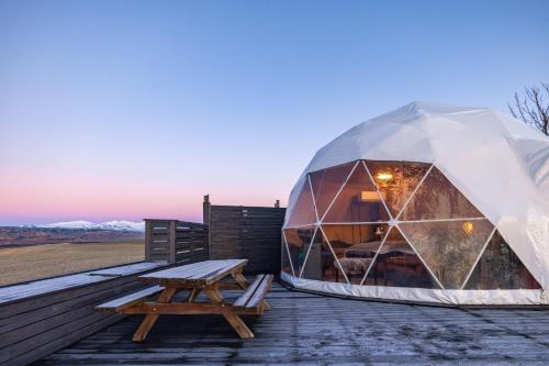 a igloo tent on a deck with a picnic table at Eyja Mork - Aurora Dome with Private Bathroom and other facilities in Hvolsvöllur