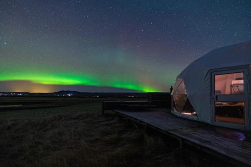 a tent under the aurora in a field at Eyja Mork - Aurora Dome with Private Bathroom and other facilities in Hvolsvöllur