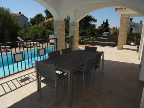 a black table and chairs on a patio with a pool at Villa KRK-4 bedrooms, 4 bathrooms with heated pool and jacuzzi, 150m from the sea in Krk