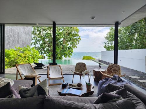 sala de estar con sofá y ventana grande en Beachfront 3 Bedrooms - AMANA Villa at Ta-Ke Residence Phuket, en Phuket