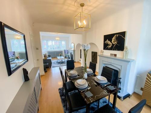 uma sala de jantar com uma mesa e uma lareira em Stunning Modern Cozy 5 star 3 bedroom house-Free Parking Greater London Metro Stations hosted by Tony em Catford