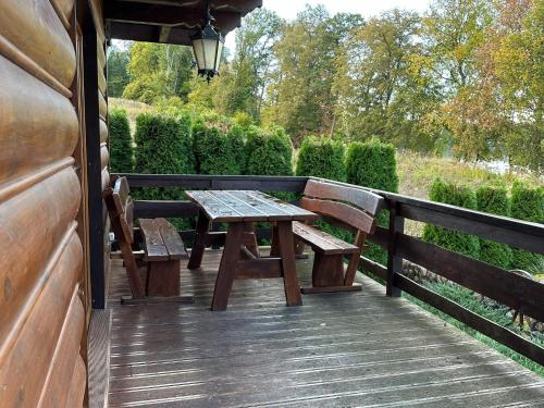 een houten terras met een picknicktafel en twee banken bij A luxury home on the shore of the lake Living room with fireplace 2 bedrooms in Lubrza
