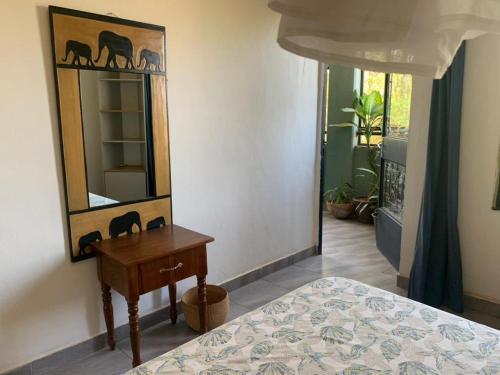 um quarto com um espelho, uma mesa e uma cama em Appartement à la Zone du Bois em Ouagadougou
