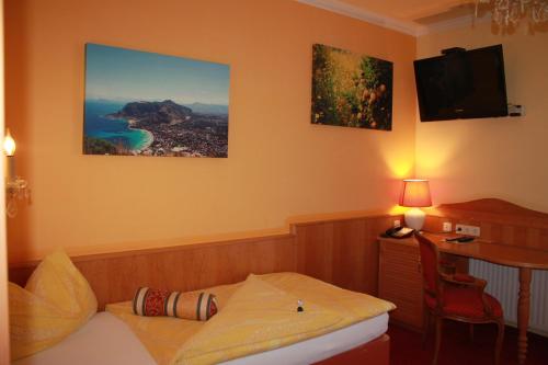 a hotel room with a bed and a desk with a television at City Hotel Neunkirchen in Neunkirchen