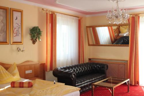 a living room with a leather couch and a mirror at City Hotel Neunkirchen in Neunkirchen