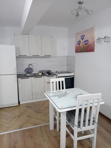 a kitchen with a white table and two chairs at Apartman M Batajnica in Batajnica