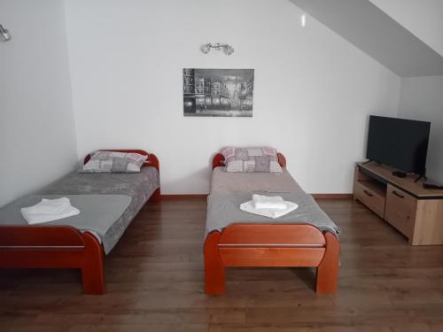 Habitación con 2 camas, TV y mesa. en Apartman M Batajnica, en Batajnica