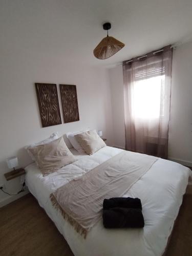 a bedroom with a white bed with a black object on it at T4 spacieux+2 terrasse vue sur picine+parking gratuit in Gagnac-sur-Garonne