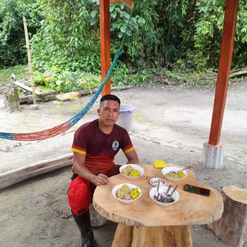Ein Mann, der an einem Tisch mit Teller Essen sitzt. in der Unterkunft Sacha Huasi in Tena