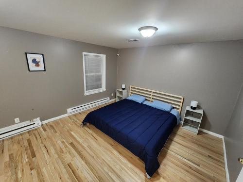 a bedroom with a blue bed and a wooden floor at Sophisticated 4-Bed Apt Close to NYC in Jersey City