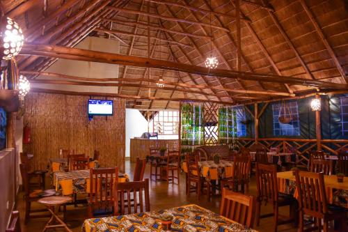 a dining room with tables and chairs and a tv at African Roots Gulu in Gulu