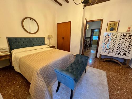 een slaapkamer met een bed, een stoel en een spiegel bij Casa Villalonga in Villalonga