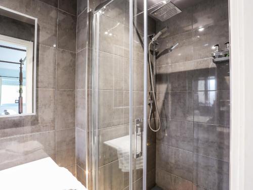 a shower with a glass door in a bathroom at Ty Siam in Newborough