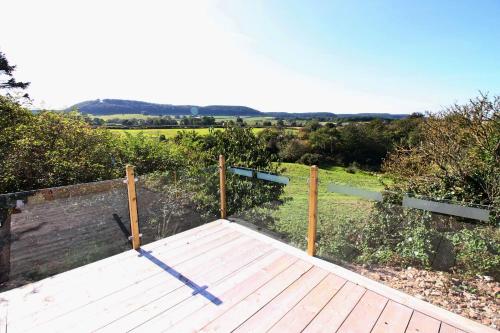 a wooden deck with a fence and a field at Applegrove Country Park, Scarborough with Private Hot Tubs in Burniston