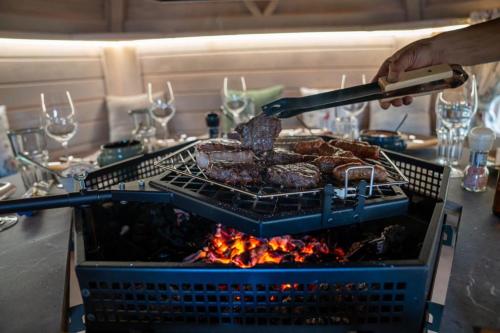 a person is cooking meat on a grill at Schilcherland Chalet Südsteiermark in Trahütten