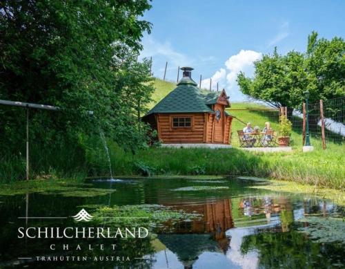 a group of people sitting on a bench near a pond at Schilcherland Chalet Südsteiermark in Trahütten