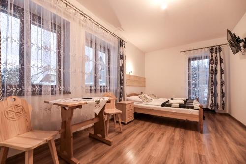 a bedroom with a bed and a table and chairs at VillaGiewont in Kościelisko