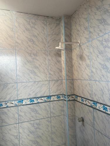 y baño con ducha y azulejos azules y blancos. en Casa Feliz, en Lima