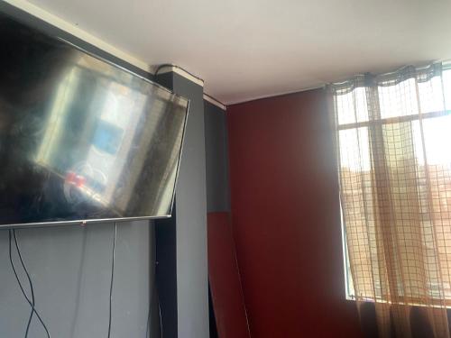 TV de pantalla plana en una habitación con ventana en Casa Feliz, en Lima