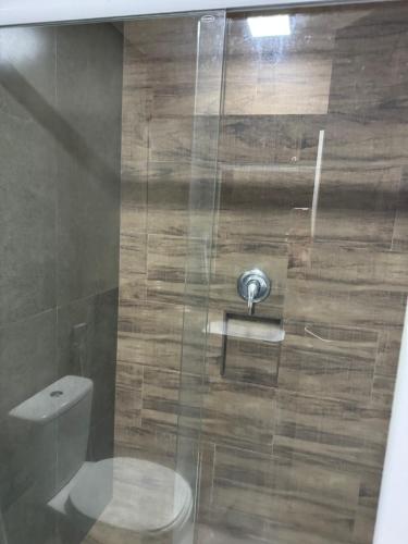a bathroom with a glass shower with a toilet at Ilusion hotel flat in Natal