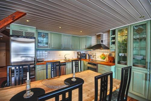 a kitchen with green cabinets and a wooden table with chairs at Rorbu Suite with sauna and steam. Henningsvær in Henningsvær