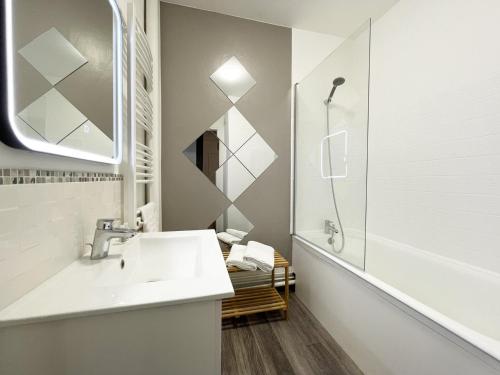 une salle de bain blanche avec un lavabo et une douche dans l'établissement L'Escapade, à Chartres