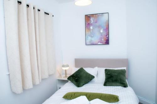 um quarto com uma cama branca e almofadas verdes em A luxury 2 bedroom flat in NN1 em Northampton
